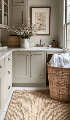 a laundry room with white cabinets and a large basket on the floor next to it