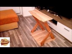 a wooden table sitting on top of a hard wood floor in a living room next to a bed