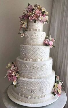 a large white wedding cake with flowers on it's side and the top tier