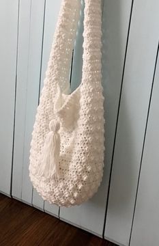 a white crocheted bag hanging on the wall next to a wooden paneled door