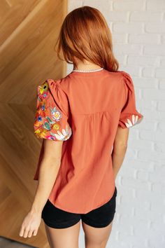 Introducing our No Concerns Embroidered Sleeve Blouse, the perfect addition to your wardrobe! Made from a woven fabric, this blouse features a stylish v-neckline with functional beaded tasseled tie, as well as balloon sleeves adorned with cheerful embroidered flowers. Lined sleeves, cased elastic sleeve cuffs, and the scooped hem and function and flair. Woven V-Neckline Functional Neck Tie Balloon Sleeve Cased Elastic Sleeve Cuff Lined Sleeve Embroidered Details Scooped Hem Beaded Tassel Details Spring Smock V-neck Blouse, Chic V-neck Smocked Top With Blouson Sleeves, Bohemian Embroidered Blouse With 3/4 Sleeves, Fitted V-neck Smock Blouse, Red Bohemian Embroidered V-neck Top, Denim Skort, Embroidered Details, Sleeve Cuff, Dress Jewelry