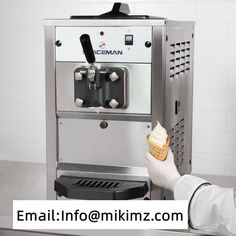 a person is holding an ice cream cone in front of a machine that makes ice cream