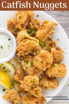 a white plate topped with fried nuggets next to a lemon wedge