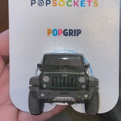 a hand holding up a plastic card with a jeep on it's front and the words popsockts popgrip