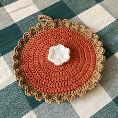 a crocheted doily on a checkered tablecloth with a small white object in the center