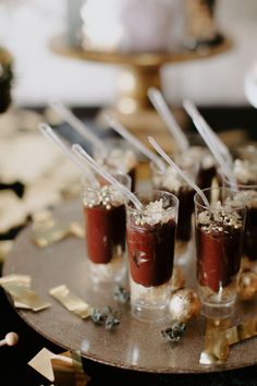 small cups filled with desserts sitting on top of a metal tray covered in confetti