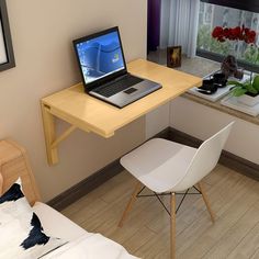 a laptop computer sitting on top of a wooden desk next to a window in a bedroom