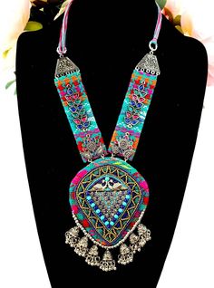 Vibrant, colorful, energetic Afghani Kuchi pendant necklace, that will go with any outfit!   It says "Look at me".  You will be noticed wearing this dramatic necklace! Colorful stiffened fabric pendant and sides, embellished with layers of textures, colors and shapes - eye-catching beads, glowing colored glass, detailed silver tone peacock and flower motif.  A row of delicate jhumka bells are suspended from the bottom. On comfortable velvet backing, to ensure a comfortable fit for you.  Adjustable length via sliding silvertone bead on cotton threads, from 7 in to 12 in.  Pendant 5"H x 3 3/4"W   The jhumka are half jhumka, made so that the jhumka lie flat and don't flip up, complimentary to the design.   Shop more necklaces here: https://www.etsy.com/shop/BoutiqueByMaryam?section_id=2169465 Bohemian Pendant Necklaces For Festivals, Handmade Necklaces For Festivals, Bohemian Beaded Pendant Necklaces For Festivals, Handmade Festival Necklaces, Blue Festival Necklace, Handmade Multicolor Necklaces For Rituals, Bohemian Multicolor Beaded Necklace With Boho Collar, Multicolor Bohemian Beaded Necklace With Boho Collar, Multicolor Bohemian Jewelry For Festival