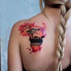 the back of a woman's shoulder with an elephant and tree tattoo on it