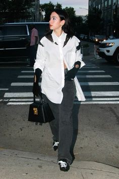 a woman in black and white is walking down the street with her hand on her hip