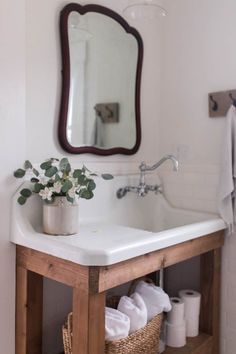 a white sink sitting under a bathroom mirror next to a wooden shelf filled with towels