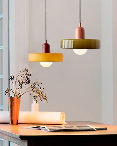 three lights hanging from the ceiling above a table with flowers in vases on it