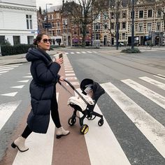 a woman is walking down the street with her stroller