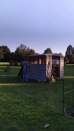 a man standing next to a trailer on top of a lush green field