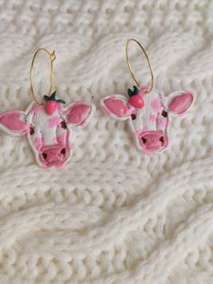 two pink and white cow earrings on a blanket