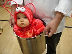 a man holding a bucket with a baby dressed as a bug in it's mouth