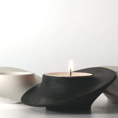 a lit candle sitting on top of a table next to two bowls and a bowl