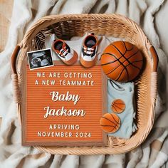 a basket filled with baby shoes and basketballs on top of a blanket next to a sign