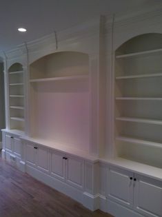 an empty room with built in bookshelves and cabinets