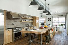 a kitchen with wooden floors and lots of lights hanging from the ceiling over the island