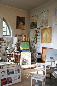 an artist's studio with paintings and ladders