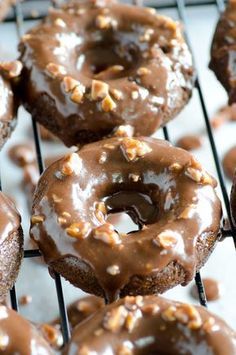 there are many chocolate donuts on the cooling rack and one is covered in icing