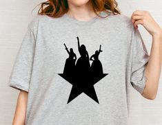 a woman wearing a star t - shirt with the silhouettes of people on it