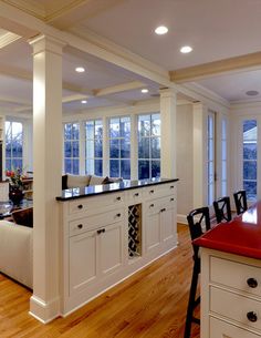 a large kitchen with white cabinets and black counter tops, along with hardwood flooring