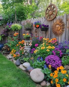 a garden with lots of flowers and rocks in the grass next to a wooden fence