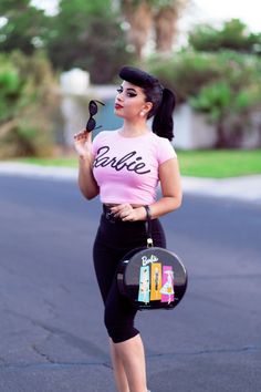 a woman in pink shirt and black leggings standing on street with handbag