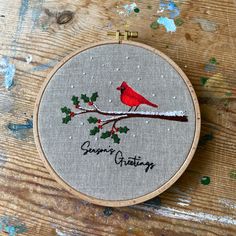 a cross stitch christmas ornament with a bird on a branch