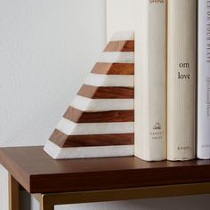 a stack of books sitting on top of a wooden shelf next to a white wall