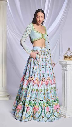 Like a breath of fresh air, our ice blue sequin-printed lehenga comes with pockets! Adorned with opulent gold embellishments, pearls, crystals and 3d flowers. Paired with a full-sleeve embroidered blouse with pearls, crystals, pink enamelled drops and glass stones along with a matching tulle dupatta filled with acrylics, crystals and a pearl border. Blue Floral Print Wedding Sets, Blue Anarkali Lehenga With Floral Print, Blue Bollywood Lehenga With Floral Print, Traditional Blue Floral Print Lehenga, Traditional Blue Lehenga With Floral Print, Blue Floral Print Choli For Festive Occasions, Festive Blue Floral Print Choli, Light Blue Sets With Intricate Embroidery, Blue Floral Print Anarkali Set For Wedding