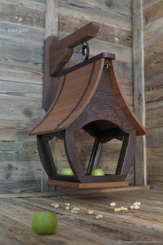 a wooden bird house with apples in the background