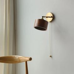 a wooden chair next to a wall mounted lamp