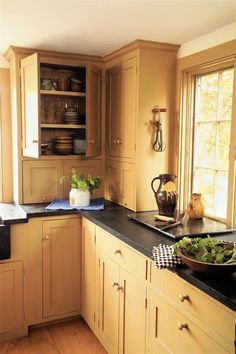 a kitchen filled with lots of wooden cabinets and black counter tops next to a window