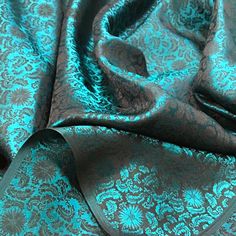 a blue and black fabric with an intricate design on the bottom, along with a dark brown ribbon