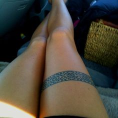 the legs of a woman with tattoos on them are sitting in a car seat next to a basket