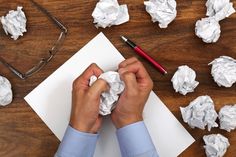 a person is making something out of paper on a wooden table with eyeglasses