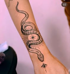 a woman's arm with a snake tattoo on it and an arrow in the middle