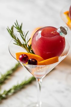 a drink in a martini glass garnished with orange slices and cherries