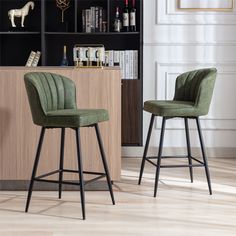 two green velvet bar stools in front of a bookcase