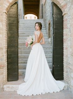 a woman in a wedding dress is standing on the stairs with her back to the camera