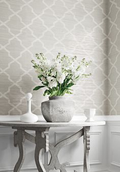 a vase with flowers sitting on top of a table in front of a wallpaper