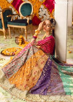 a woman sitting on the ground in a colorful dress with flowers around her neck and hands behind her head