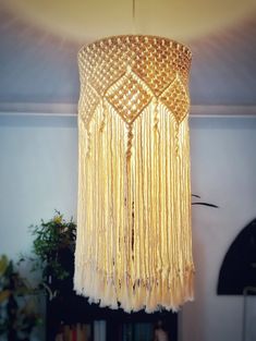 a chandelier hanging from the ceiling in a room with bookshelves and plants