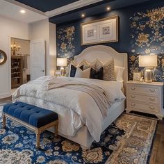 a bedroom with blue and gold wallpaper, white bedding, and an ornate rug