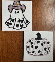 two small embroidered pumpkins are sitting on a wooden table with black and white designs