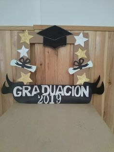 a graduation decoration made out of wood and paper with stars on it, in front of a wooden wall