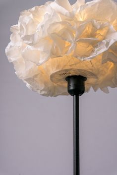 a lamp that is on top of a black pole and has paper flowers on it